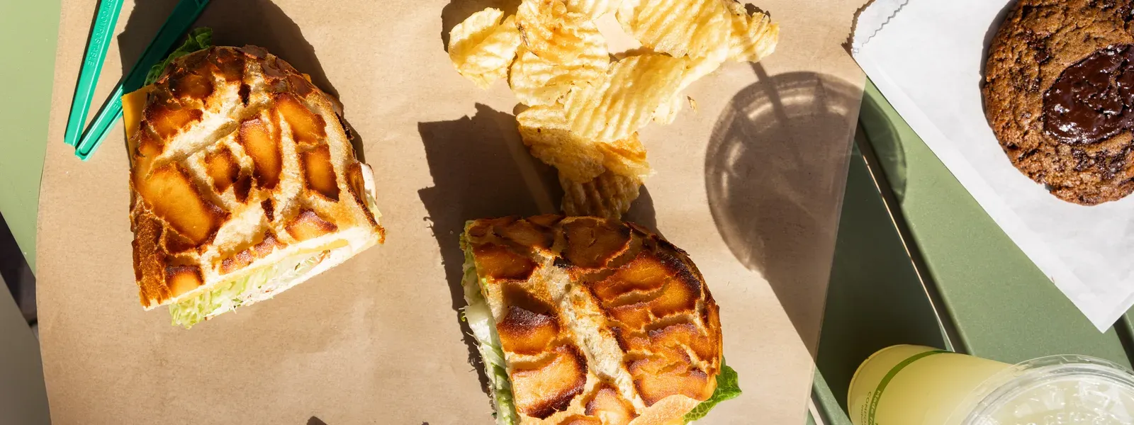 Catering spread: sandwiches, Caesar salad, kettle chips, and fresh lemonade